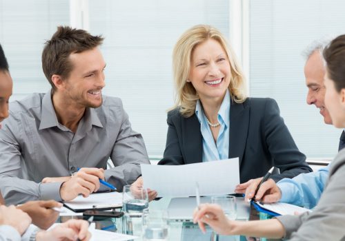 Group Of Happy Coworkers Discussing In Conference Room